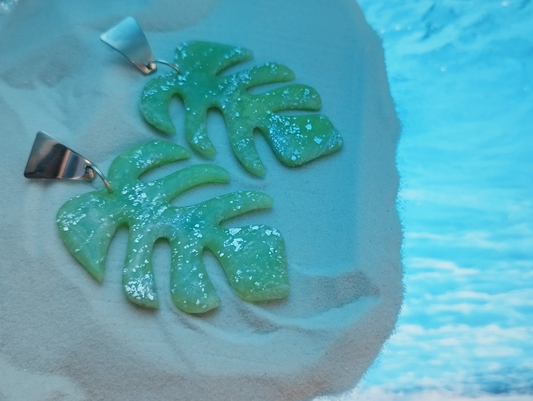 Handmade Polymer Clay Earrings. The base is Stainless steel (hypoallergenic) silver in colour in a reverse triangle shape attached with a silver colour jump ring which is attached to the Monstera Leaf in Light Green Quartz colour with silver sparkles covered with UV Resin for added shine. 
