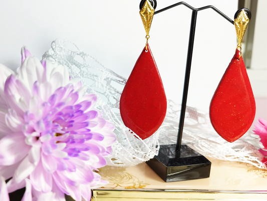 Teardrop Red with Gold sparkles Handmade Polymer Clay Earrings. The base is Stainless steel gold colour in a Kite shape attached with a gold colour jump ring which is attached to a Red Teardrop with gold sparkles covered with UV Resin for added shine. 