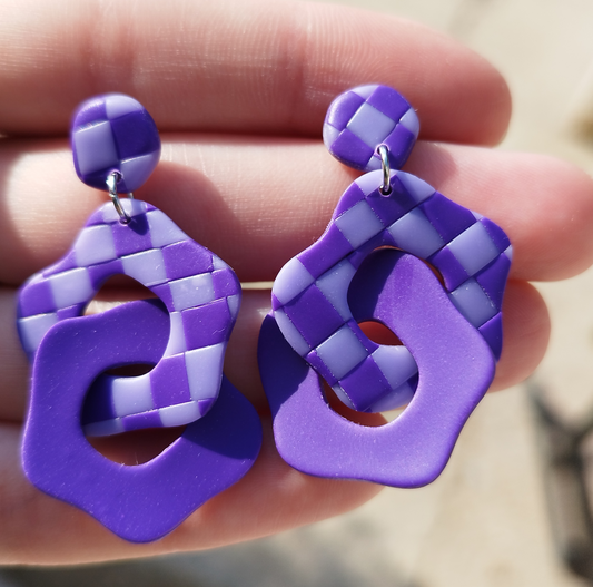 Abstract Flower Checkerboard Interlocking in Violet and Periwinkle Handmade Polymer Clay Earrings. The base of the Earrings is an abstract convex polygon attached to a jump ring to the Abstract Flower shape hanging from it with the same colour scheme. This is interlocked with an Abstract Flower shape in Violet colour.